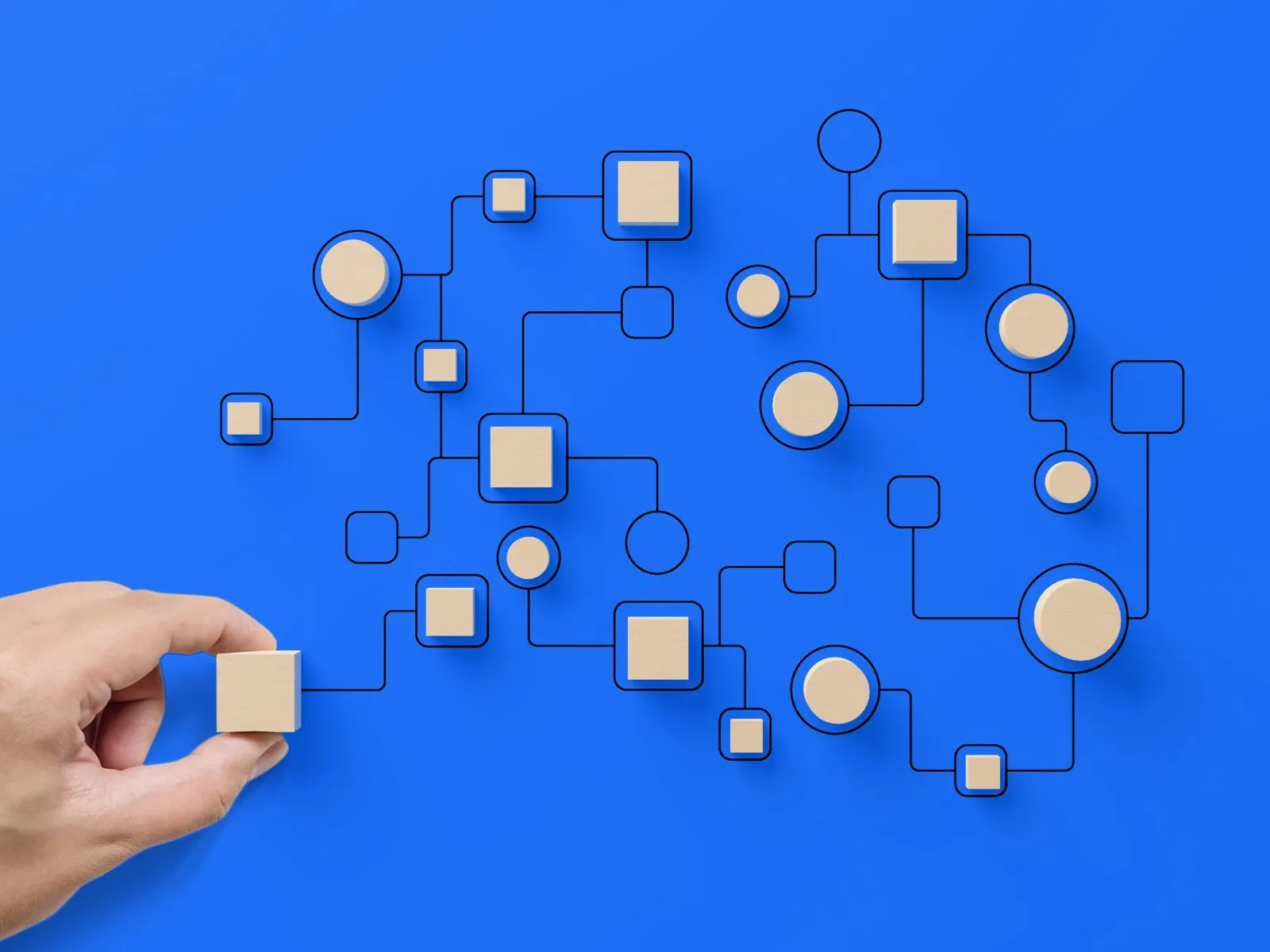 Hand placing a wooden block into a connected workflow diagram on a blue background