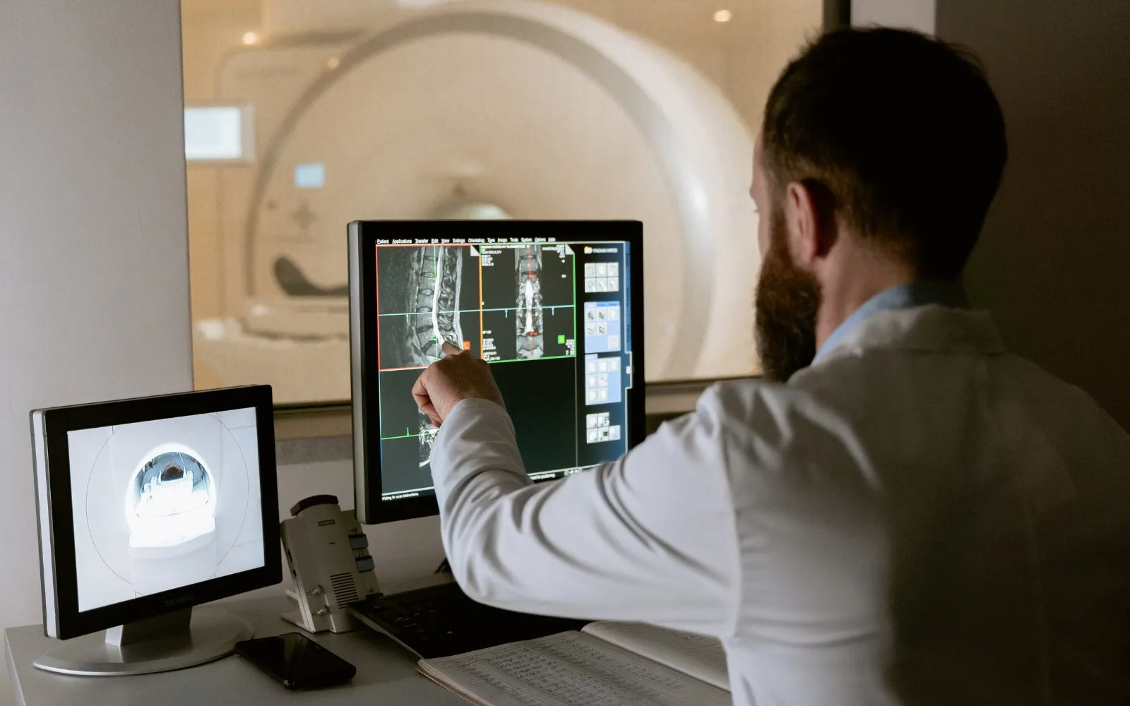 Clinician reviewing spine MRI scans on a monitor in front of an MRI scanner